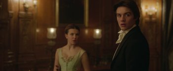 Movie still from “Enola Holmes 2” (2022), directed by Harry Bradbeer – A man and a woman standing next to each other in a room; Medium shot, Over the shoulder angle