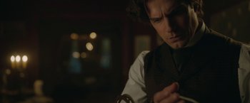 Movie still from “Enola Holmes 2” (2022), directed by Harry Bradbeer – A man in a suit and tie looking at his cell phone; Close Up shot, Over the shoulder angle