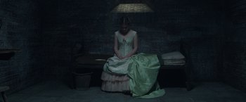 Movie still from “Enola Holmes 2” (2022), directed by Harry Bradbeer – A woman sitting on a bench wearing a green dress; Wide shot, High angle