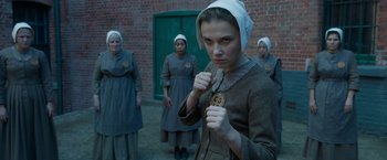 Movie still from “Enola Holmes 2” (2022), directed by Harry Bradbeer – A group of women dressed in old - fashioned clothing; Medium shot, Over the shoulder angle