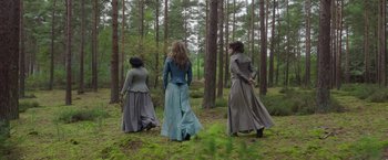Movie still from “Enola Holmes 2” (2022), directed by Harry Bradbeer – A group of women in long dresses walking through the woods; Wide shot, Low angle