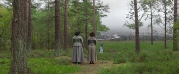 Movie still from “Enola Holmes 2” (2022), directed by Harry Bradbeer – Two women are standing in a field looking at a tree; Extreme Wide shot, High angle