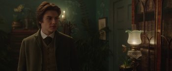 Movie still from “Enola Holmes 2” (2022), directed by Harry Bradbeer – A man in a suit and tie standing in front of a door; Medium shot, Over the shoulder angle