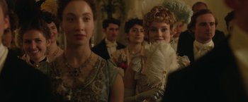 Movie still from “Enola Holmes 2” (2022), directed by Harry Bradbeer – A group of people dressed up in fancy clothing; Close Up shot, Over the shoulder angle