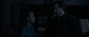 Movie still from “Enola Holmes 2” (2022), directed by Harry Bradbeer – A man and a woman standing next to each other in the dark; Medium shot, Over the shoulder angle