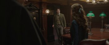 Movie still from “Enola Holmes 2” (2022), directed by Harry Bradbeer – A man in a suit and tie standing next to a woman; Medium shot, Over the shoulder angle