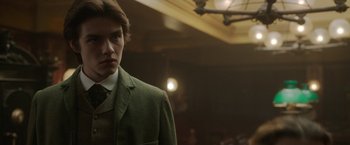 Movie still from “Enola Holmes 2” (2022), directed by Harry Bradbeer – A man in a suit and tie standing in a room; Close Up shot, Low angle