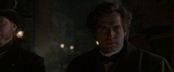 Movie still from “Enola Holmes 2” (2022), directed by Harry Bradbeer – A person wearing a suit and a bow tie; Close Up shot, Over the shoulder angle