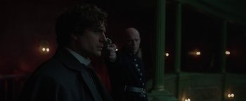 Movie still from “Enola Holmes 2” (2022), directed by Harry Bradbeer – Two men are standing in the dark holding a gun; Close Up shot, Over the shoulder angle