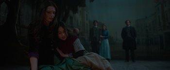 Movie still from “Enola Holmes 2” (2022), directed by Harry Bradbeer – A group of people standing in a dark area; Medium shot, Over the shoulder angle