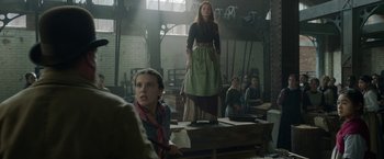 Movie still from “Enola Holmes 2” (2022), directed by Harry Bradbeer – A woman standing in front of a group of people; Medium shot, Over the shoulder angle