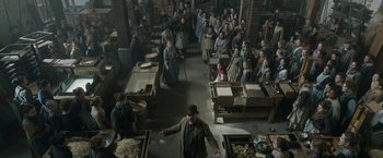 Movie still from “Enola Holmes 2” (2022), directed by Harry Bradbeer – A group of people in a room with boxes; Wide shot, High angle