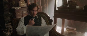 Movie still from “Enola Holmes 2” (2022), directed by Harry Bradbeer – A man sitting in a chair looking at a newspaper; Close Up shot, Over the shoulder angle
