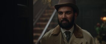 Movie still from “Enola Holmes 2” (2022), directed by Harry Bradbeer – A man with a beard wearing a top hat and a coat; Close Up shot, Over the shoulder angle