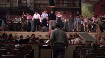 Movie still from “Kiss Me Kate” (1953), directed by George Sidney – A group of people standing on a stage in front of a crowd; Wide shot, Low angle
