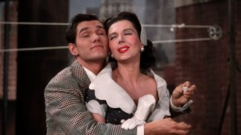 Movie still from “Kiss Me Kate” (1953), directed by George Sidney – A man and a woman embracing each other in front of a building; Medium shot, High angle