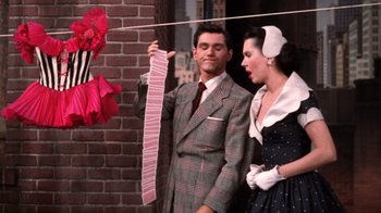 Movie still from “Kiss Me Kate” (1953), directed by George Sidney – A man and a woman holding up a string of playing cards; Medium shot, High angle