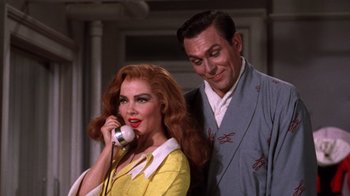 Movie still from “Kiss Me Kate” (1953), directed by George Sidney – A man and a woman standing next to each other on a phone; Medium shot, Low angle