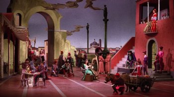 Movie still from “Kiss Me Kate” (1953), directed by George Sidney – A group of people sitting on the ground in front of a building; Extreme Wide shot, High angle