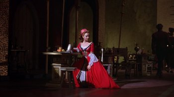 Movie still from “Kiss Me Kate” (1953), directed by George Sidney – A woman dressed in a red dress sitting at a table; Wide shot, Low angle