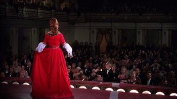 Movie still from “Kiss Me Kate” (1953), directed by George Sidney – A woman in a red dress on stage in front of an audience; Wide shot, Over the shoulder angle
