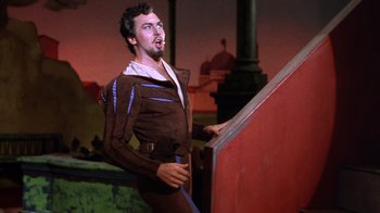 Movie still from “Kiss Me Kate” (1953), directed by George Sidney – A man in a brown jacket standing next to a red wall; Medium shot, Low angle