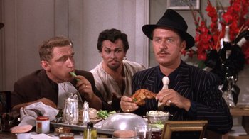 Movie still from “Kiss Me Kate” (1953), directed by George Sidney – A group of men sitting at a dinner table eating food; Medium shot, Over the shoulder angle