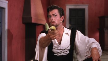 Movie still from “Kiss Me Kate” (1953), directed by George Sidney – A man holding an apple in his right hand; Close Up shot, Low angle