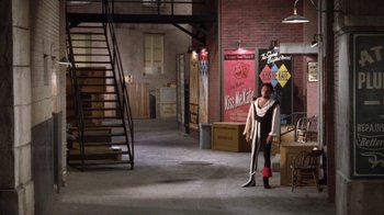 Movie still from “Kiss Me Kate” (1953), directed by George Sidney – A woman in a warehouse holding a pair of skis; Wide shot, High angle