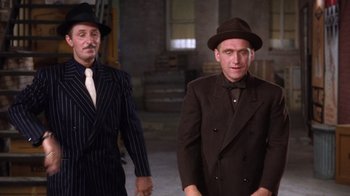 Movie still from “Kiss Me Kate” (1953), directed by George Sidney – A man in a suit and a man in a hat; Medium shot, Low angle