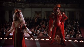 Movie still from “Kiss Me Kate” (1953), directed by George Sidney – A man and a woman dressed in red are performing on stage; Wide shot, Low angle