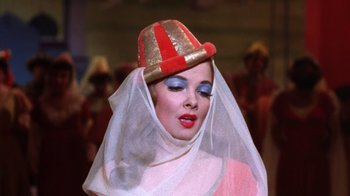 Movie still from “Kiss Me Kate” (1953), directed by George Sidney – A woman in a red and white hat with a veil; Close Up shot, Low angle