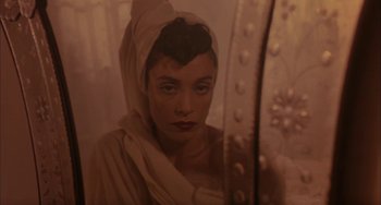 Movie still from “Kiss of the Spider Woman” (1985), directed by Hector Babenco – A woman with a head covering looking into a bathroom mirror; Close Up shot, High angle