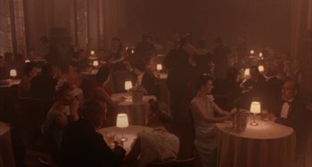 Movie still from “Kiss of the Spider Woman” (1985), directed by Hector Babenco – A group of people sitting at tables in a room; Wide shot, High angle