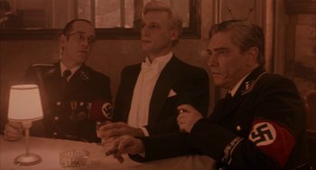 Movie still from “Kiss of the Spider Woman” (1985), directed by Hector Babenco – A group of men sitting around a table; Medium shot, Low angle