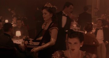 Movie still from “Kiss of the Spider Woman” (1985), directed by Hector Babenco – A group of people dressed up in formal attire; Medium shot, Over the shoulder angle