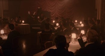 Movie still from “Kiss of the Spider Woman” (1985), directed by Hector Babenco – A group of people sitting at a table in front of candles; Wide shot, High angle