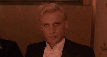 Movie still from “Kiss of the Spider Woman” (1985), directed by Hector Babenco – A man with blonde hair wearing a suit and bow tie; Close Up shot, High angle