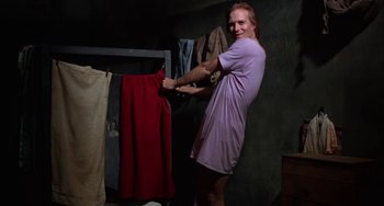 Movie still from “Kiss of the Spider Woman” (1985), directed by Hector Babenco – A man in a purple shirt hanging clothes on a clothesline; Medium shot, Low angle