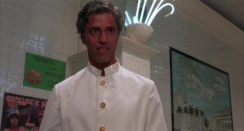 Movie still from “Kiss of the Spider Woman” (1985), directed by Hector Babenco – A man in a white suit standing in front of a building; Close Up shot, Low angle