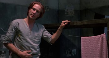 Movie still from “Kiss of the Spider Woman” (1985), directed by Hector Babenco – A man standing in front of a wall with a cross on it; Medium shot, Low angle