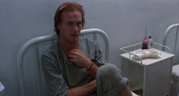 Movie still from “Kiss of the Spider Woman” (1985), directed by Hector Babenco – A man sitting on a hospital bed in a hospital room; Medium shot, Low angle