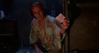Movie still from “Kiss of the Spider Woman” (1985), directed by Hector Babenco – A man holding a piece of paper while standing in a dark room; Close Up shot, Low angle