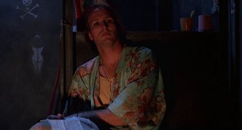 Movie still from “Kiss of the Spider Woman” (1985), directed by Hector Babenco – A man sitting on a chair in a room; Close Up shot, Low angle