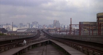 Movie still from “Kiss of the Spider Woman” (1985), directed by Hector Babenco – A view of a train track with a city in the background; Extreme Wide shot, High angle