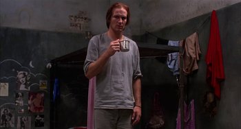 Movie still from “Kiss of the Spider Woman” (1985), directed by Hector Babenco – A man holding a cup in his hand; Medium shot, Low angle