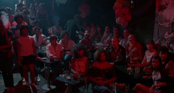 Movie still from “Kiss of the Spider Woman” (1985), directed by Hector Babenco – A group of people sitting in a dark room; Wide shot, High angle