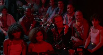 Movie still from “Kiss of the Spider Woman” (1985), directed by Hector Babenco – A group of people sitting at a table in a room; Medium shot, High angle