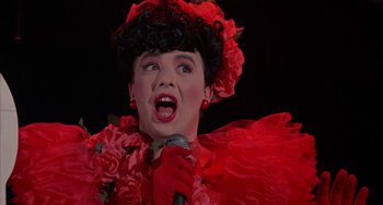 Movie still from “Kiss of the Spider Woman” (1985), directed by Hector Babenco – A woman in a red dress singing into a microphone; Close Up shot, Low angle
