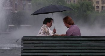 Movie still from “Kiss of the Spider Woman” (1985), directed by Hector Babenco – Two men sitting on a bench under an umbrella; Wide shot, High angle